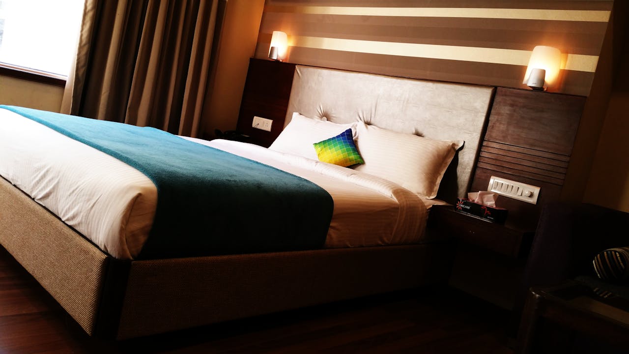 The Art of Drawing Readers In: Your attractive post title goes here A contemporary hotel room featuring a large bed with colorful pillows, warm lighting, and modern interior design.