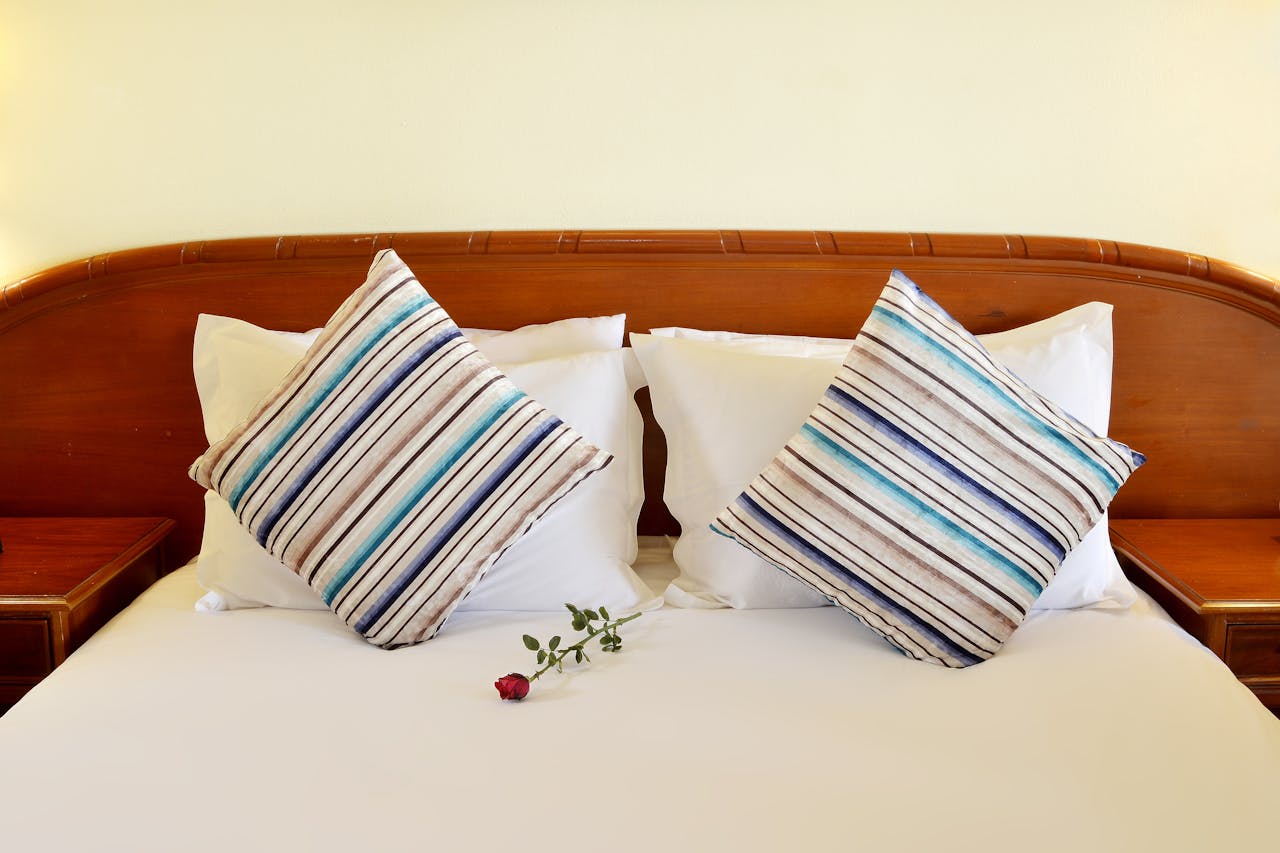Crafting Captivating Headlines: Your awesome post title goes here Elegant hotel bed setting with striped pillows and a red rose for a touch of romance.